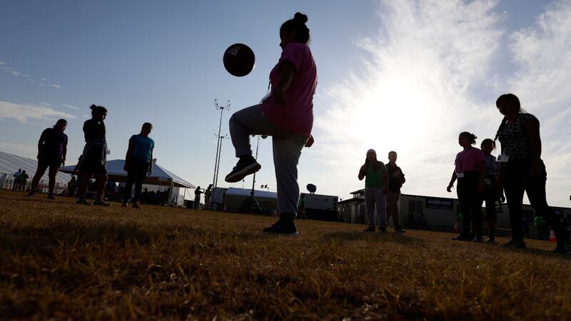 ARCHIVO - Inmigrantes juegan al fútbol en un centro de acogida del gobierno estadounidense...