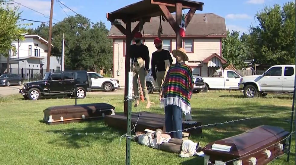 The Halloween display shows two figures with nooses around their necks. They are wearing red...