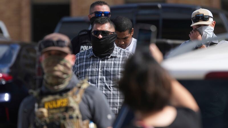 Agentes federales escoltan a un hombre a un autobús después de ser detenido después de una...